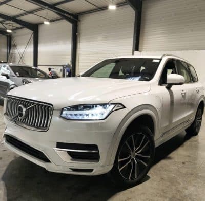 Volvo XC90 T8 blanc de 2021 vu de trois quarts avant, feux à LED allumés